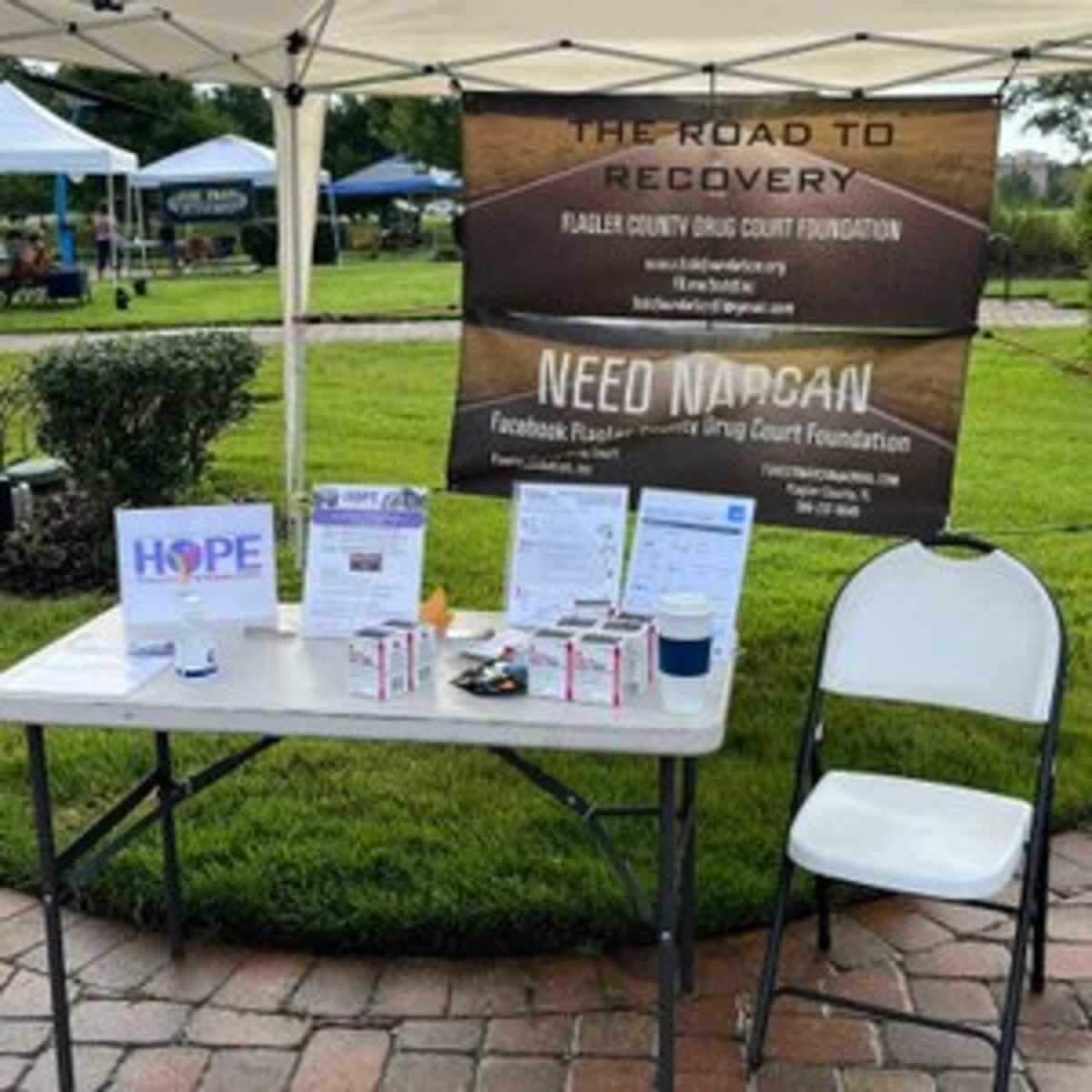 The Foundation's outreach table at a Flagler County community event, with free Narcan and information handouts laid out under a canopy.